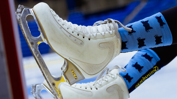 Close up of ice skates and Bobcat patterned socks on someone's feet