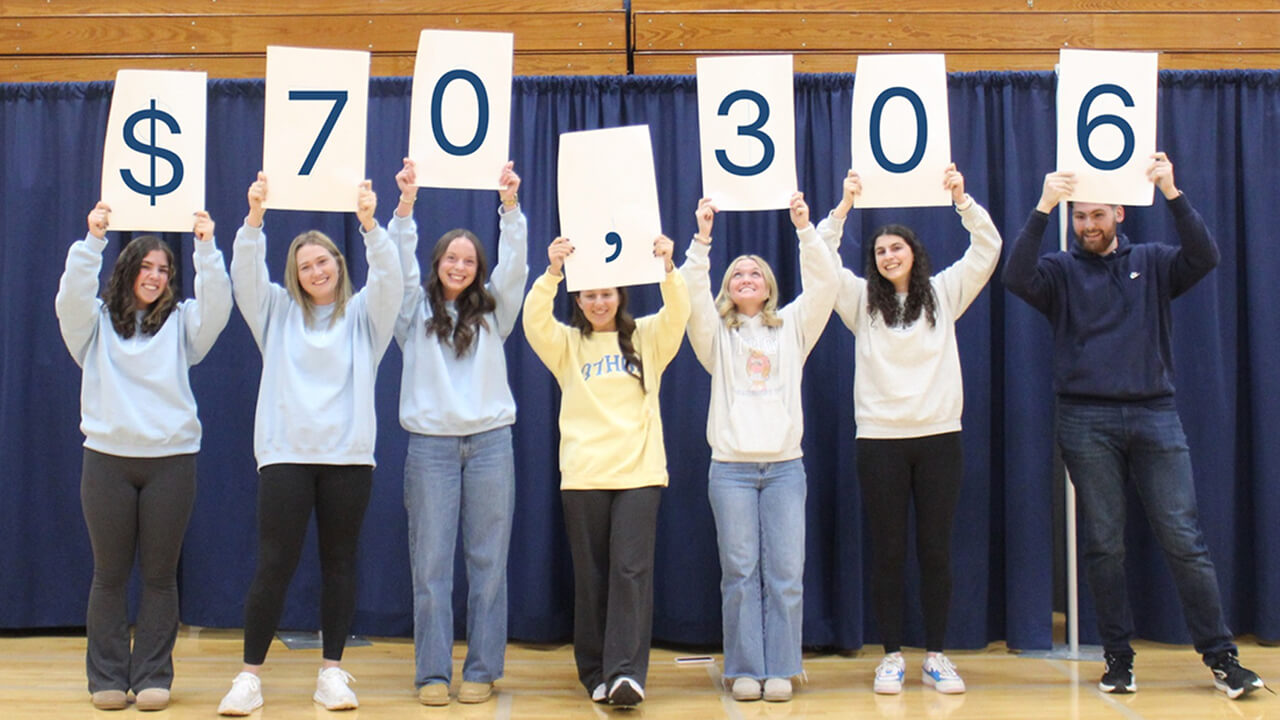 Students hold sign announcing the $70,306 raised