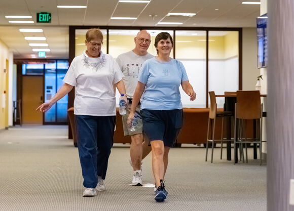 Three adults wearing comfortable clothes walk inside for the Bobcat Stride program