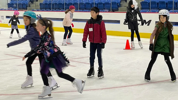 Several children in helmets skate on Quinnipiac's ice rink