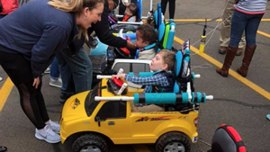 A student smiles with a small child in his custom-built rehabilitation vehicle