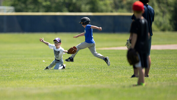 Children play baseball Quinnipiac's baseball field on a sunny day