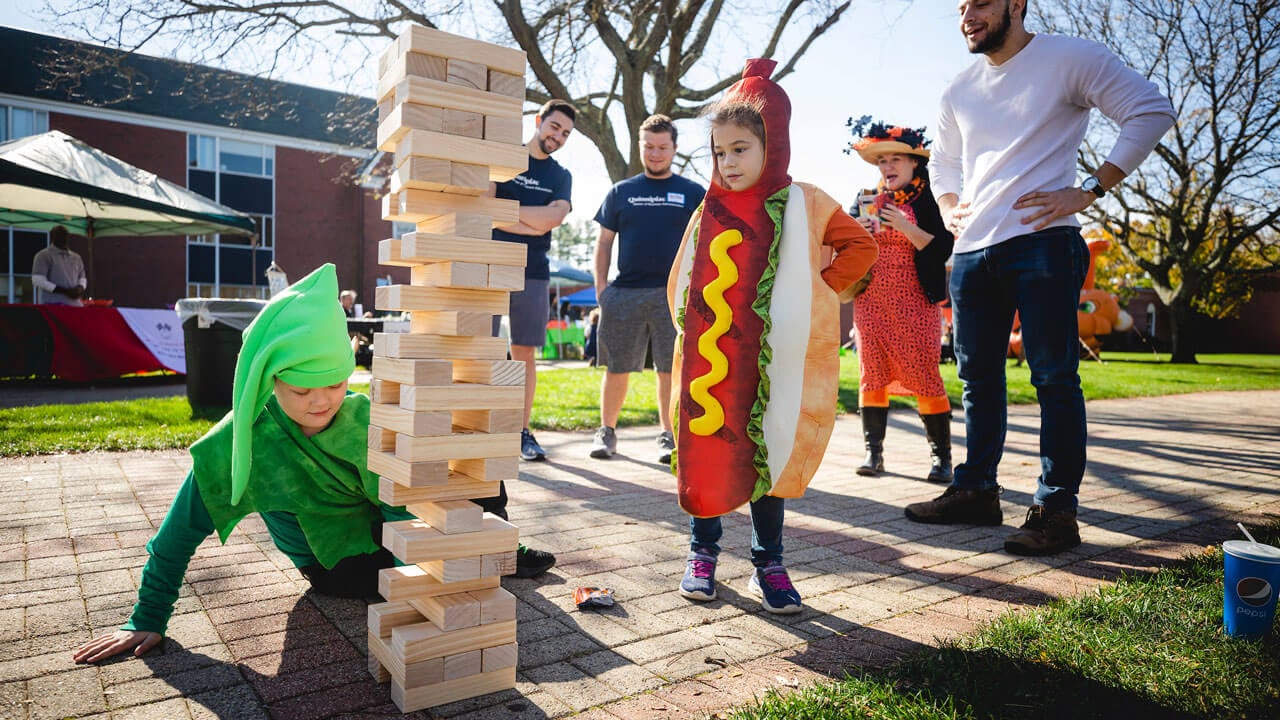 Children dressed in costumes playing outdoor Jenga