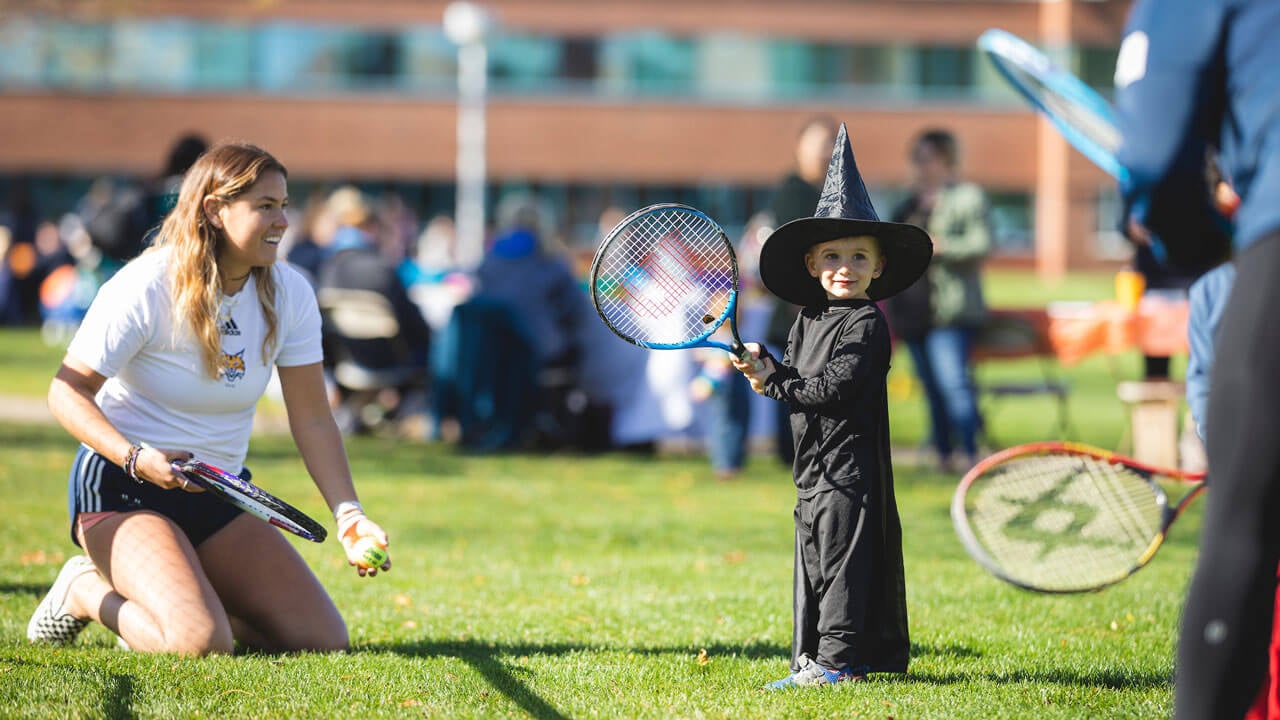 Tennis team and child dressed as a witch holding tennis rackets