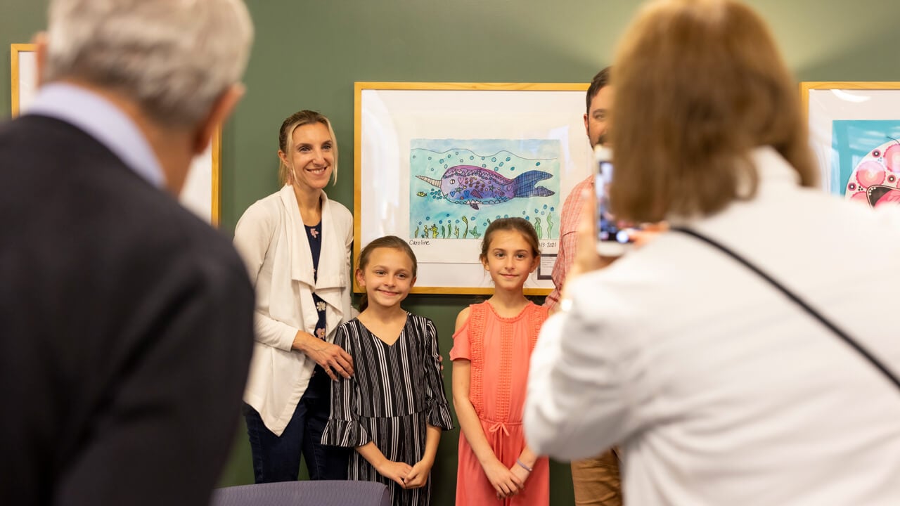 Two local elementary students smile with artwork in the Quinnipiac School of Education