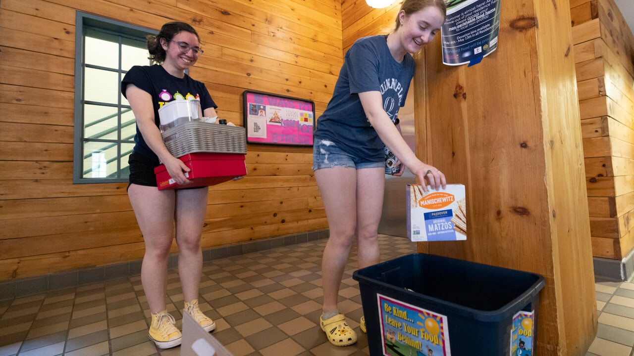 Two Quinnipiac students put donated food into a collection bin