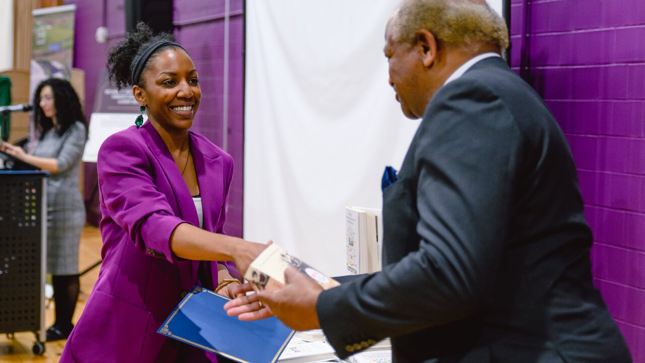 An entrepreneur program graduate shakes hands as she receives her diploma